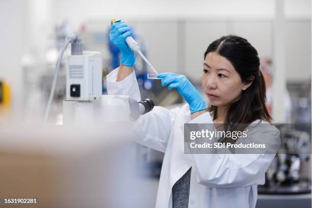 female doctoral student conducts experiments in college lab - pipet laboratoriumapparatuur stockfoto's en -beelden