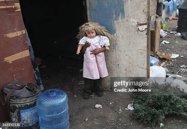 Mirna Guadelupe plays in front of her modest home with a doll found at the Tirabichi garbage dump on March 5, 2013 in Nogales, Mexico. About 30...