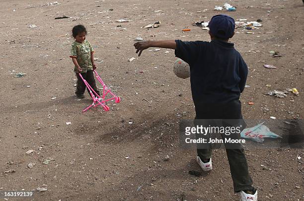 Siblings Mirna Guadelupe and Carlos Roman play with toys found at the Tirabichi garbage dump on March 5, 2013 in Nogales, Mexico. About 30 families...