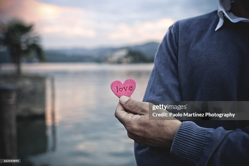 Detail of a man's hand holding a small pink heart