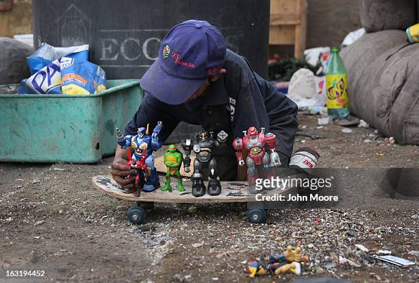 Carlos Roman plays with toys found while he and family members were working at the Tirabichi garbage dump on March 5, 2013 in Nogales, Mexico. About...