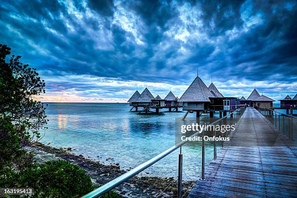 tropical paradise luxury over water resort at sunset - new caledonia stock pictures, royalty-free photos & images