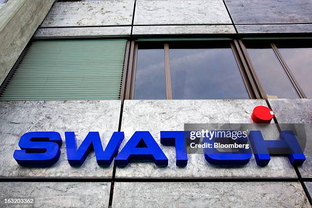 Logo sits above the entrance to the headquarters of Swatch AG in Bienne, Switzerland, on Wednesday, March 6, 2013. Swatch Group AG, the biggest maker...