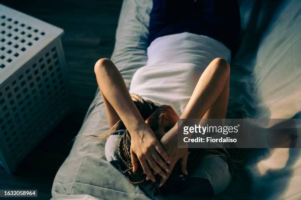 portrait of a woman lying on the sofa - hoofdpijn vrouw stockfoto's en -beelden