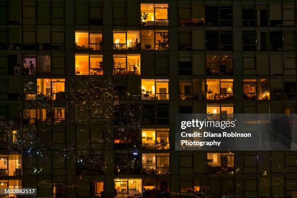 view of apartment windows at night as seen from the brooklyn bridge with lights from the bridge reflected, brooklyn - flat stockfoto's en -beelden