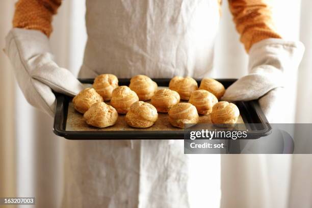 man holding oven tray of cream puff - relámpago de crema fotografías e imágenes de stock