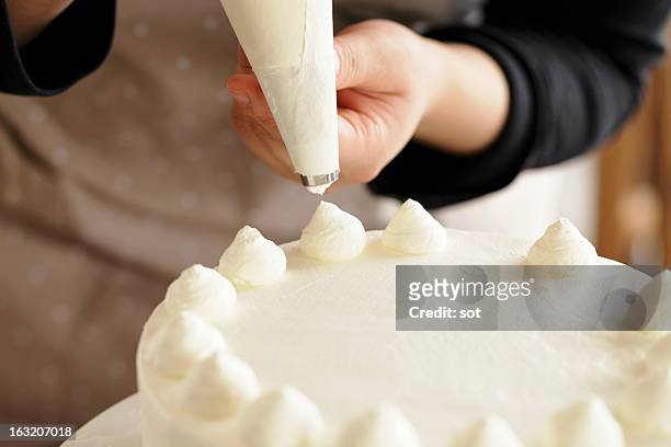 woman decorating whipped cream on cake - cucinare un dolce foto e immagini stock