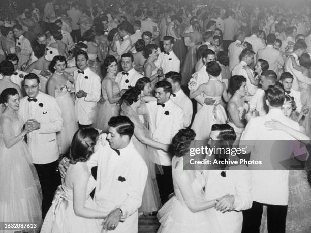 Elevated view of students at a formal dance, 1950s.The men are wearing white dinner jackets and the women white ball gowns.