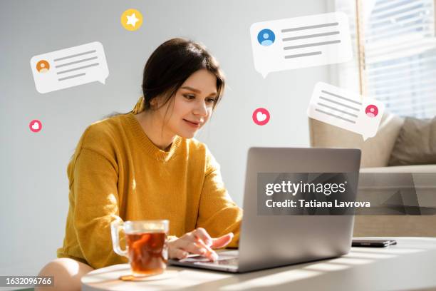 beautiful young woman in yellow cardigan using laptop in a sunny room. she chatting with her friends and colleagues. virtual reality, modern communication, work place, surfing the net, surfing the net - suggestive stock pictures, royalty-free photos & images
