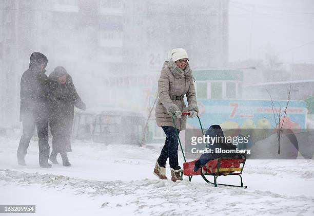 Woman pushes a child on a sled along a snow-coverered path outside a Lenta LLC supermarket in Prokopyevsk, Kemerevo region, Russia, on Wednesday,...