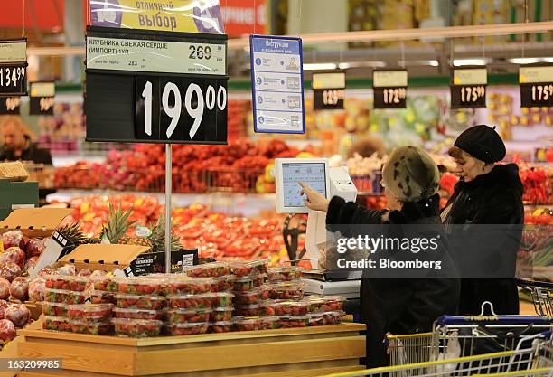 Customers use an electronic scale to check the price of their fresh fruit and vegetables inside a Lenta LLC supermarket in Prokopyevsk, Kemerevo...