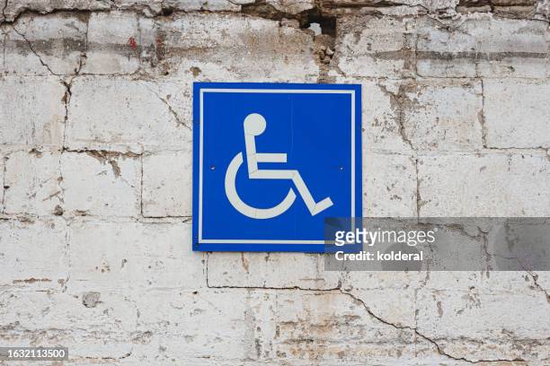 disabled parking sign attached to the cracked white wall - handicap parking space stock pictures, royalty-free photos & images