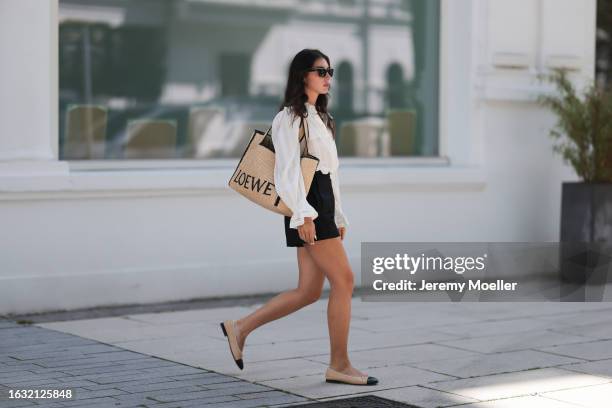 Milena Karl is seen wearing black sunglasses from Chanel, a gold necklace, a white shirt with puffy sleeves from Isabel Marant, a large tote bag from...