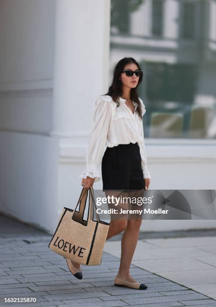 Milena Karl is seen wearing black sunglasses from Chanel, a gold necklace, a white shirt with puffy sleeves from Isabel Marant, a large tote bag from...