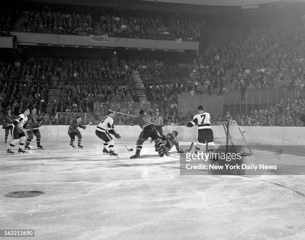 With New York Rangers goalie Lorne "Gump" Worsley down on the ice and defenseman Lou Fontinato waving his stick wildly, Detroit's Gordie Howe watches...