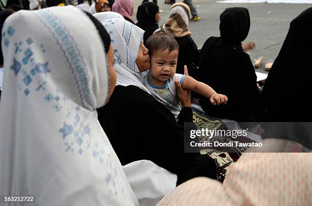 Baby is held by a woman during prayers in the Muslim community of Maharlika Village on March 6, 2013 in Taguig, Philippines. The peace rally was held...