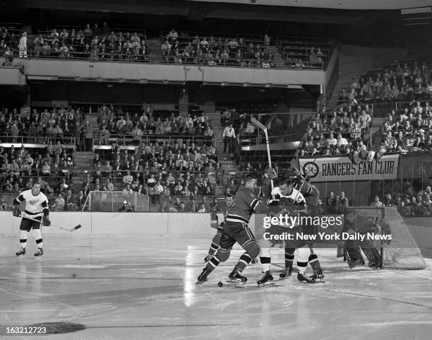 Sticks slash wildly through the air at Madison Square Garden as Gordie Howe of the Detroit Red Wings fights for possession of the puck with New York...