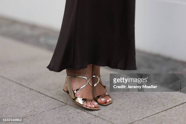 Milena Karl is seen wearing a black maxi skirt from Massimo Dutti, and shiny golden strap sandals with wedge heels from Jimmy Choo on August 22, 2023...
