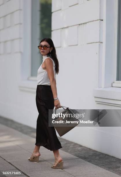 Milena Karl is seen wearing black sunglasses with orange lenses from Lexxola, golden earrings from Bottega Veneta, a creme-white sleeveless top from...