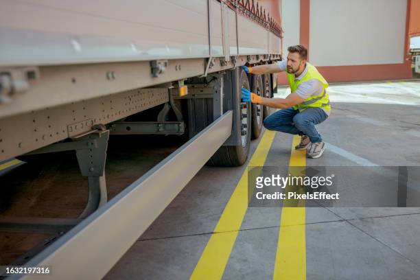 truck driver checking the truck's safety - vrachtwagen banden stockfoto's en -beelden