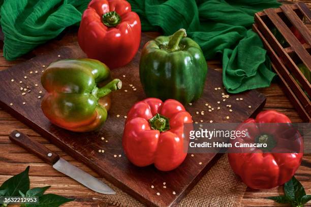 fresh red and green sweet pepper on a wooden rustic board - groene paprika stockfoto's en -beelden