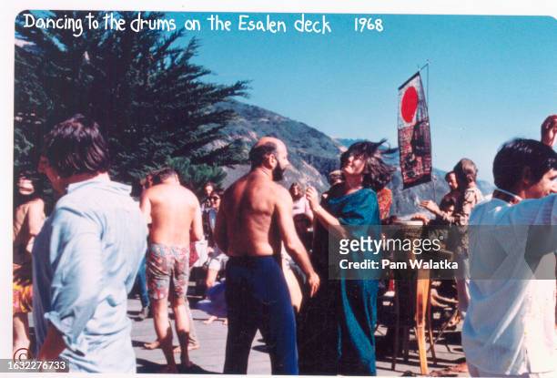 Among others, American psychologist Will Schutz dances with educator Betty Fuller as conga drummers perform on the deck at the Esalen Institute deck,...