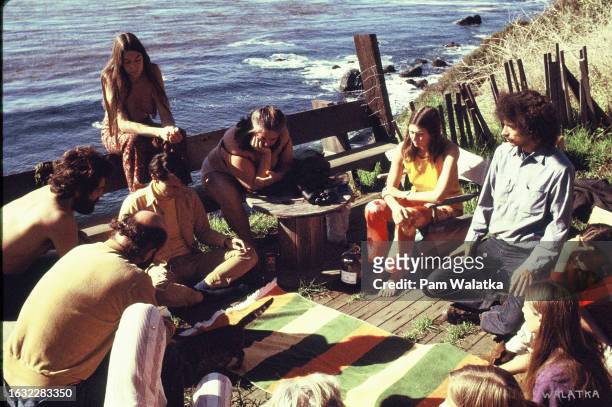 View of a group of people seated in a circle on the deck of the Farm House, overlooking the Pacific Ocean, at the Esalen Institute, overlooking the...