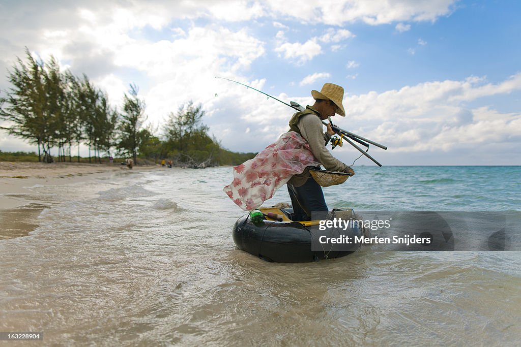 Tube fisherman with rods on beach