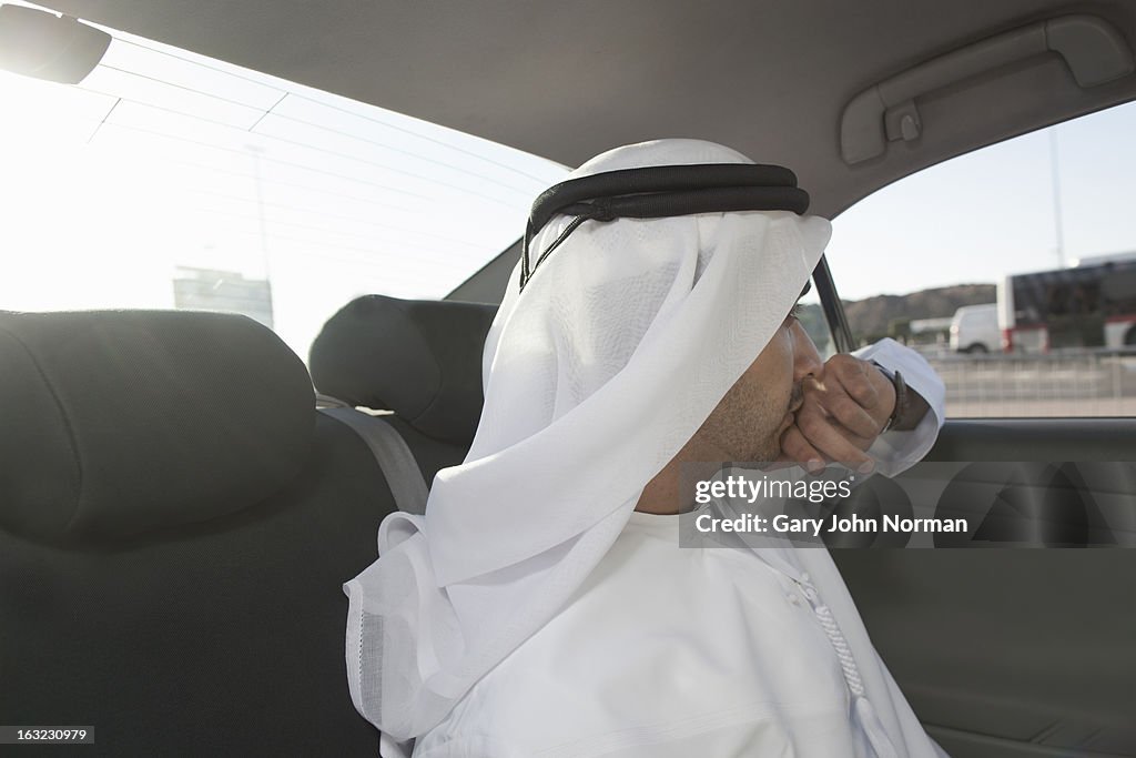 Arab businessman in traditional dress in car