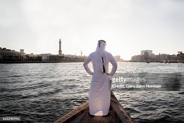 arab businessman in traditional dress, dubai creek - united arab emirates cityscape stock pictures, royalty-free photos & images