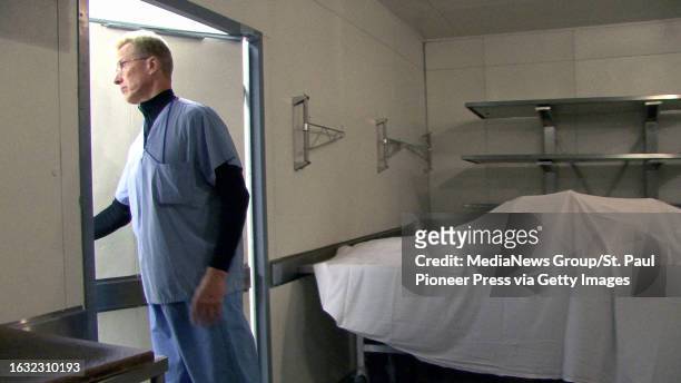 Ramsey County Medical Examiner Dr. Michael McGee walks from refrigeration to an autopsy room at the morgue in St. Paul, Minn. On Nov. 25 in...