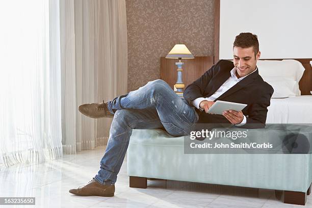 young  man using digital tablet in hotel room - man in suite holding tablet stockfoto's en -beelden