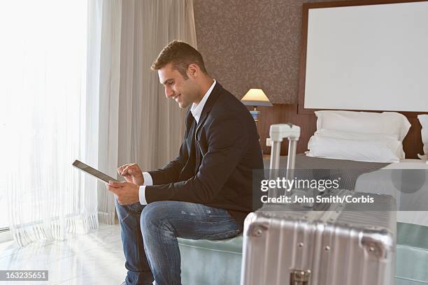 young  man using digital tablet in hotel room - man in suite holding tablet stockfoto's en -beelden