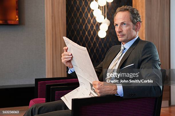businessman reading newspaper in living room - three quarter length stock pictures, royalty-free photos & images