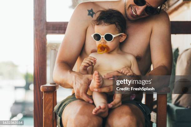a happy man relaxing outdoors with his cute naked baby girl (looking away) during his summer vacation - pacifier stock pictures, royalty-free photos & images