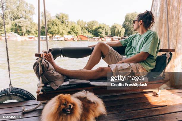 a handsome man looking away while sitting outdoors - lazy river stock pictures, royalty-free photos & images