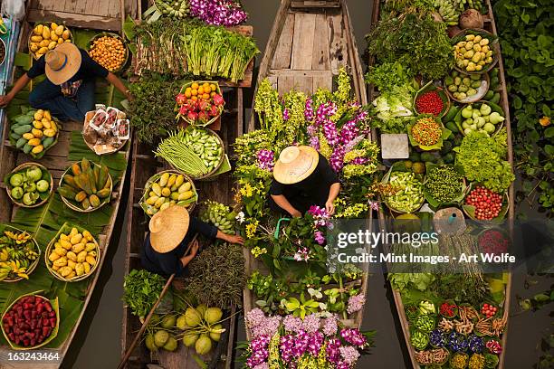 a floating market on a canal in thailand. boats laden with fresh produce, vegetables and fruit. market traders. - marché flottant photos et images de collection