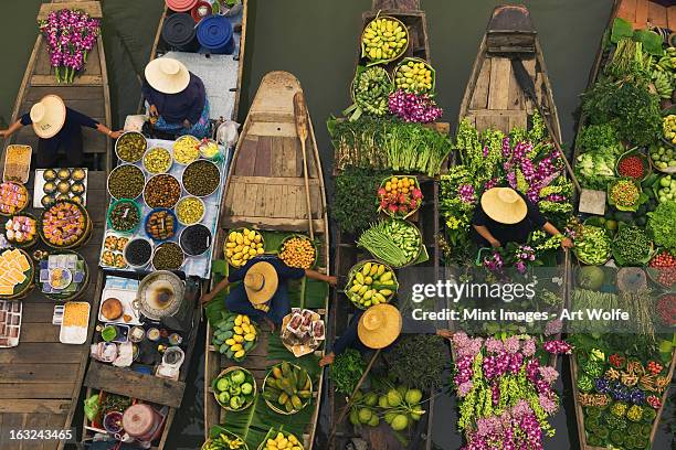 a floating market on a canal in thailand. boats laden with fresh produce, vegetables and fruit. market traders. - marché flottant photos et images de collection