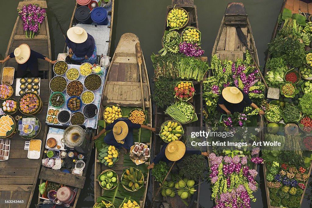 A floating market on a canal in Thailand. Boats laden with fresh produce, vegetables and fruit. Market traders.