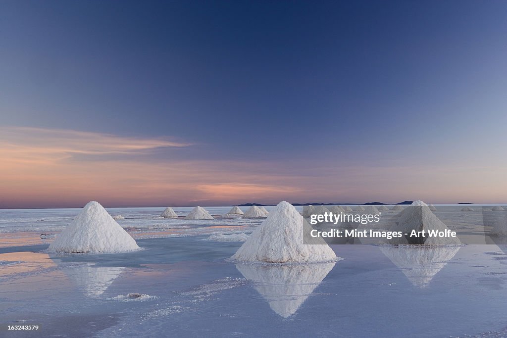 Bolivia, Salar de Uyuni salt flats. Piles of white salt crystals. Harvesting the natural minerals. Sunrise.