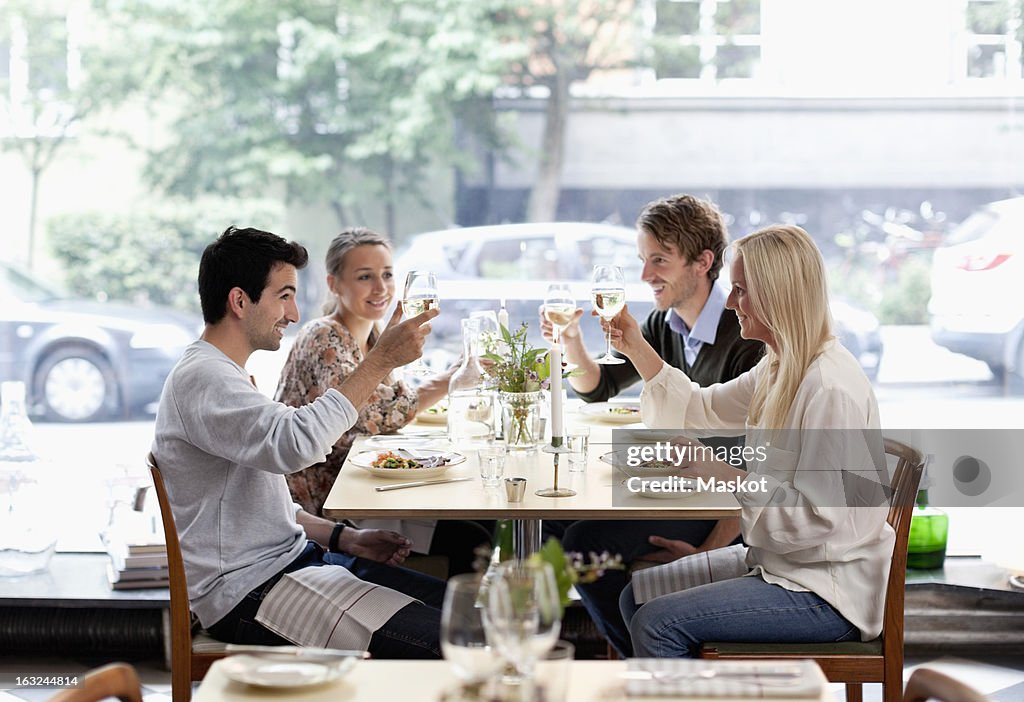 Group of friends toasting wineglasses at restaurant table