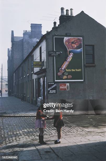 Two girls on the corner of Little Ship Street, Belfast, Northern Ireland, June 1955. A chalked grafitti drawing on the building is captioned; 'This...
