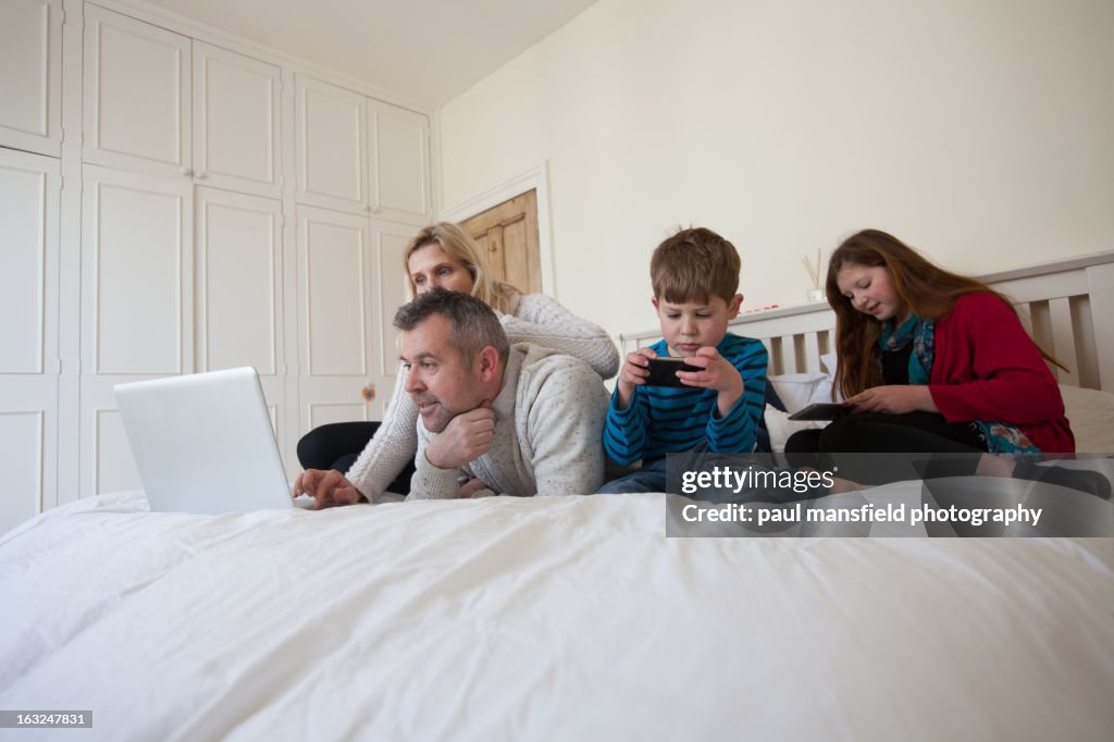 Family using technology in the bedroom