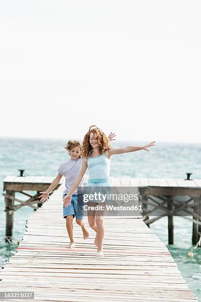spain, girl and boy running on jetty at he sea - 飛行機のまね ストックフォトと画像