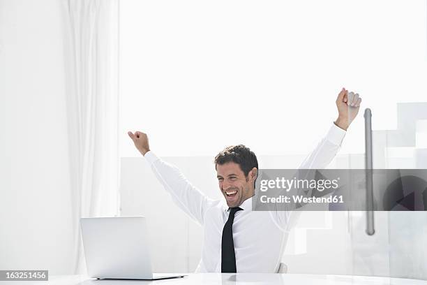 spain, businessman excited while looking laptop, smiling - bras homme fond blanc photos et images de collection