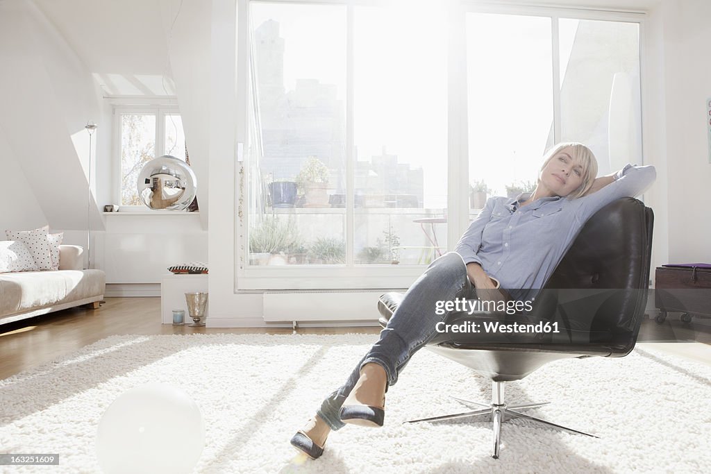 Germany, Bavaria, Munich, Woman relaxing on chair in living room