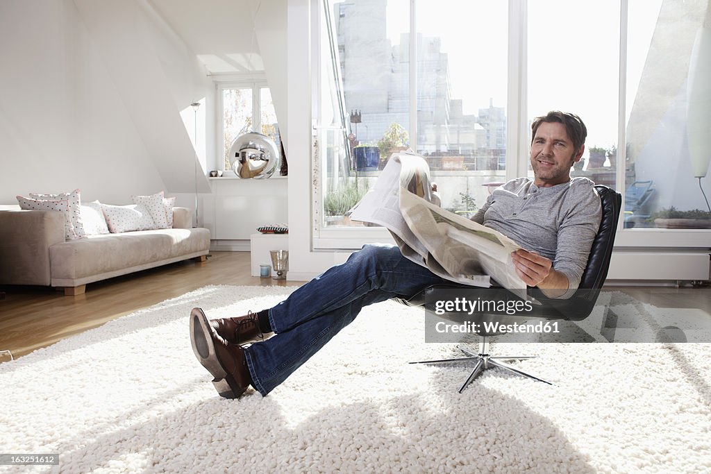 Germany, Bavaria, Munich, Man reading newspaper in living room