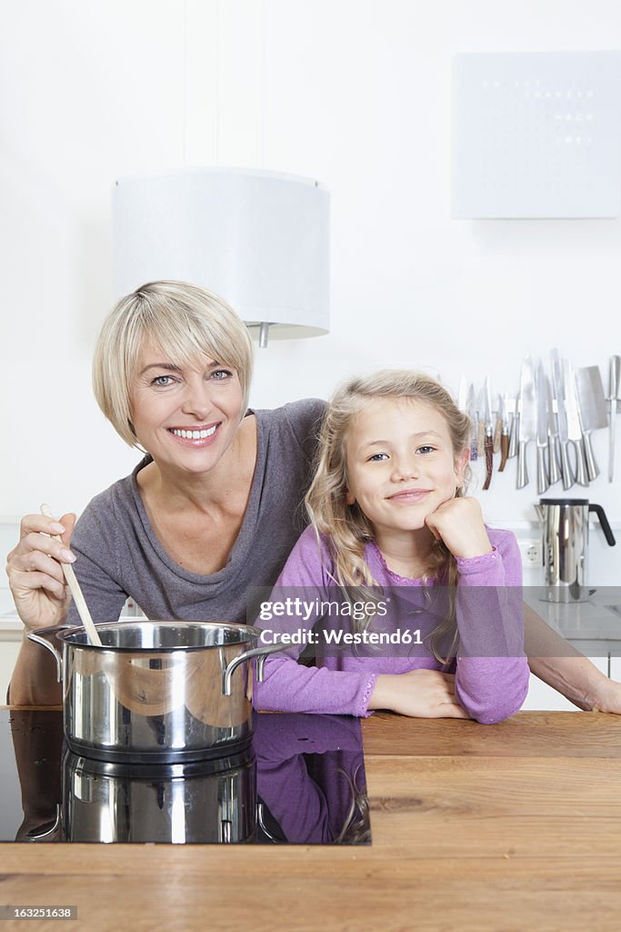 Germany, Bavaria, Munich, Mother and daughter preparing food, smiling, portrait