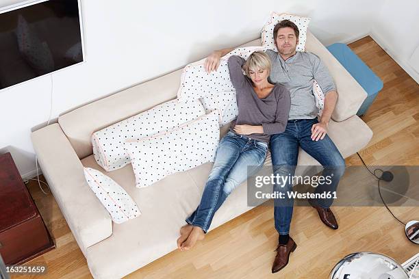 germany, bavaria, munich, mature couple relaxing on sofa - woman 45 sleeping stock-fotos und bilder