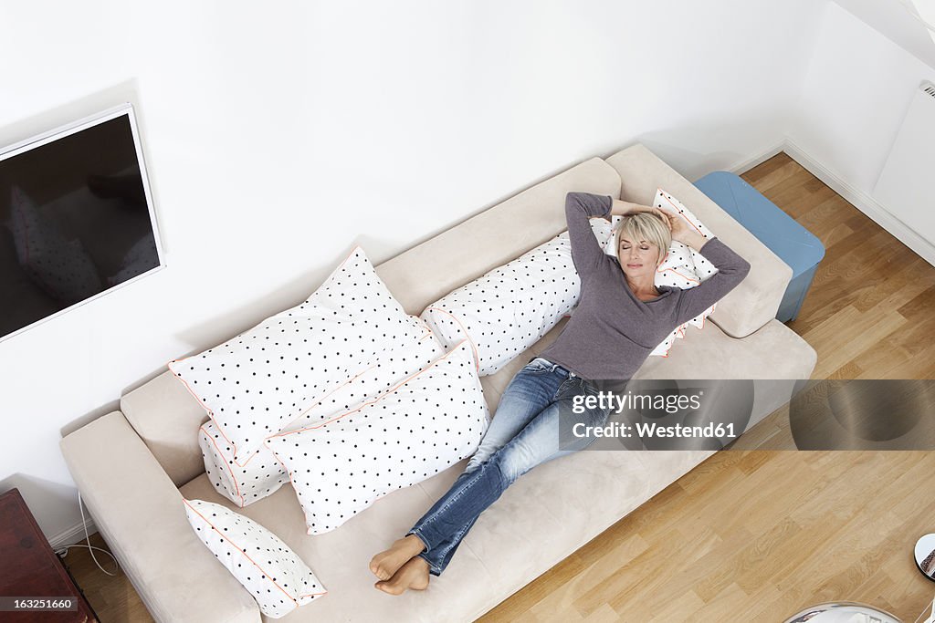 Germany, Bavaria, Munich, Woman relaxing on couch in living room